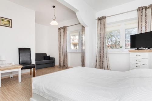 a white bedroom with a bed and a desk and a tv at Krab in Rewal