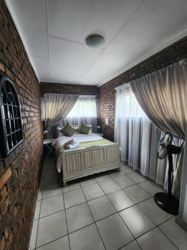 - une chambre avec un lit et un mur en briques dans l'établissement Apartment at Kitchener, à Middelburg