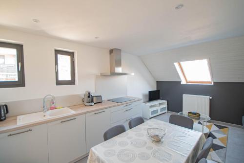 a kitchen with a table and a sink and a table and chairs at Maison L'Aiguille - 2 appartements, 5 chambres et table d'hôtes au pied de la montagne à la station de Laye in Laye
