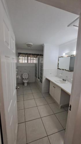 a white bathroom with a toilet and a sink at A-List Villas in Rodney Bay Village