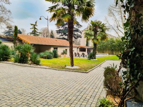a brick driveway with palm trees in front of a house at Lyon Faubourg - Saint Priest in Saint-Priest