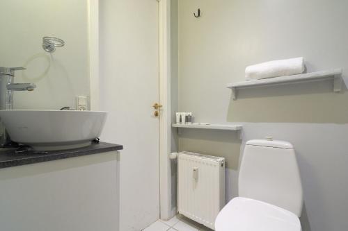 a white bathroom with a sink and a toilet at Stylish Ground Floor Flat Perfect for Couples in Copenhagen