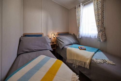 Una pequeña habitación con dos camas y una ventana. en Nirvana Coastal Retreat Holiday Home, en Cayton