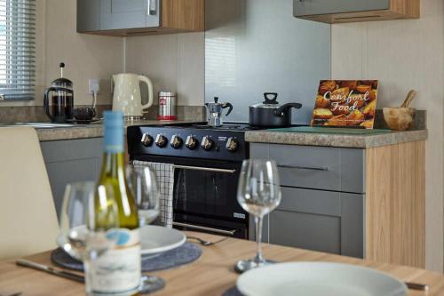 cocina con fogones y mesa con copas de vino en Nirvana Coastal Retreat Holiday Home, en Cayton