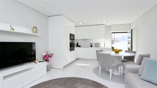a white kitchen and living room with a table and a tv at Marina Retreat - CleverDetails, for 2 adults and 2 children, Jacuzzi, near the Marina and the beach in Vilamoura
