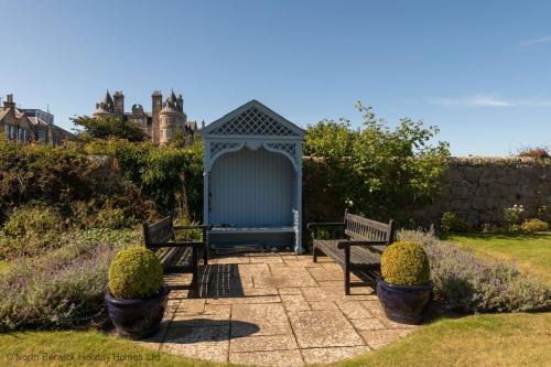 a gazebo with two benches in a garden at St Colms Main House in North Berwick