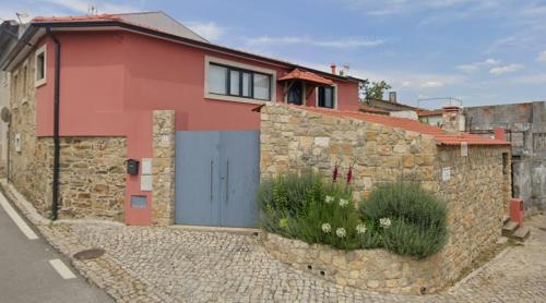 a red house with a blue door and a stone wall at A Casa da Carmita in Pedrógão Grande