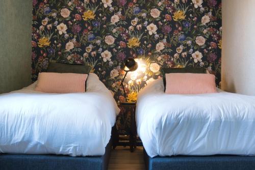 two beds in a room with a floral wallpaper at appartement Elperhof 16B in Schoonloo
