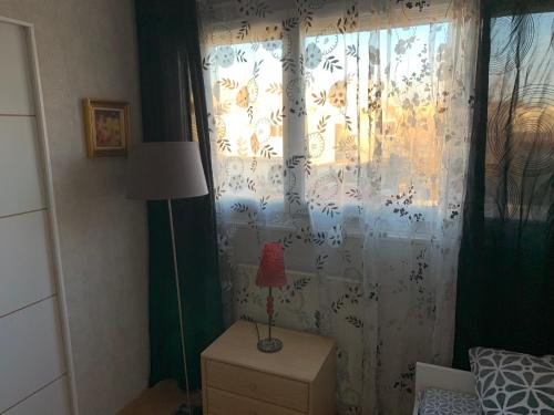 a bedroom with a window with a lamp on a dresser at Jolie chambre Nenuphar dans belle maison in Vaulx-en-Velin