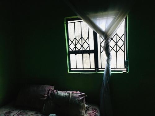 ventana con cortina y cama en una habitación en Purple, en Durban