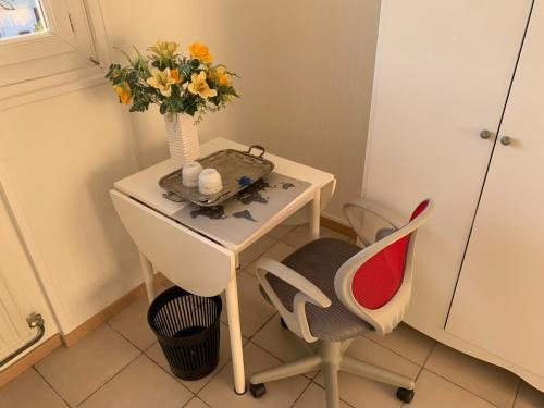 a table with a vase of flowers and a chair at Chambre tout confort Saphir 1 à 3 P dans belle maison in Vaulx-en-Velin