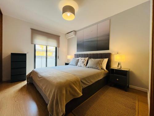 a bedroom with a large bed and a window at Condomínio Ondas do Mar -Coastal Comfort- in Olhão