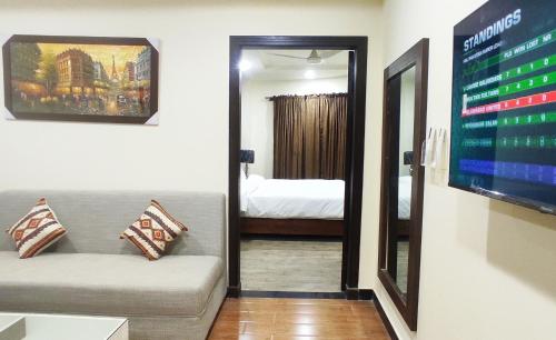 a room with a couch and a tv and a bedroom at Hotel Daffodils in Rawalpindi