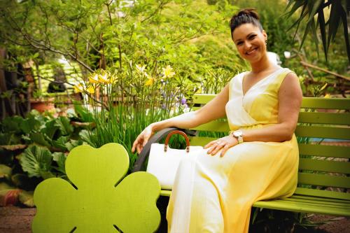 a woman in a yellow dress sitting on a green bench at Haus am Kurpark in Schömberg