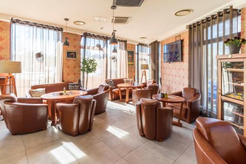 um restaurante com mesas, cadeiras e janelas em Wellton Riga Hotel & SPA em Riga