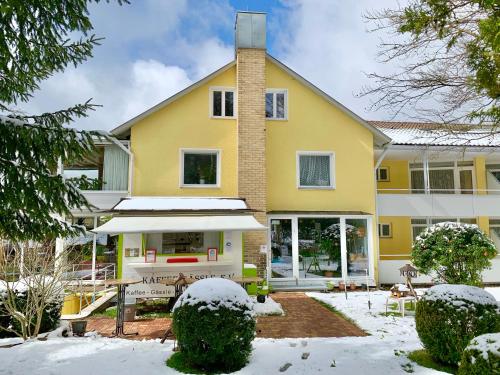 a yellow house with snow in the yard at Haus am Kurpark in Schömberg