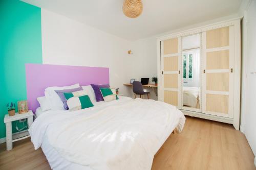 1 dormitorio con 1 cama blanca grande y paredes coloridas en Casita - Comme une petite maison - Parking gratuit en Valence