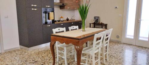 - une cuisine avec une table en bois et des chaises blanches dans l'établissement Marilè, à Carmiano