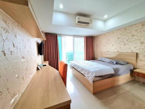 Schlafzimmer mit einem Bett und einem Schreibtisch mit einem TV in der Unterkunft La Grande Merdeka Apartment in Bandung
