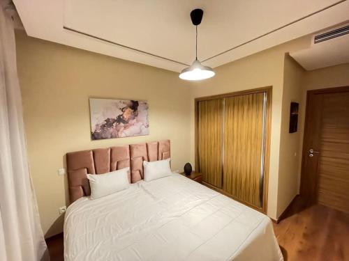 um quarto com uma cama grande e lençóis brancos em Chic & cosy Flat Near Airport lockbox fast wifi em Nouaceur