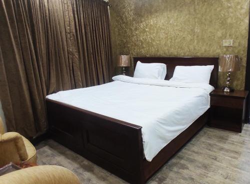 a bedroom with a large bed with white sheets and pillows at Hotel Daffodils in Rawalpindi