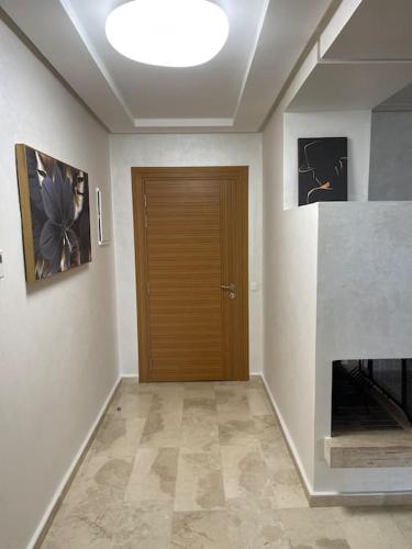 a hallway with a wooden door and paintings on the wall at Chic & cosy Flat Near Airport lockbox fast wifi in Nouaceur