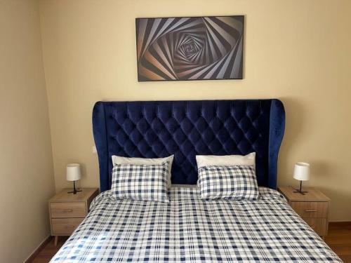 a bed with a blue headboard and two night stands at Chic & cosy Flat Near Airport lockbox fast wifi in Nouaceur