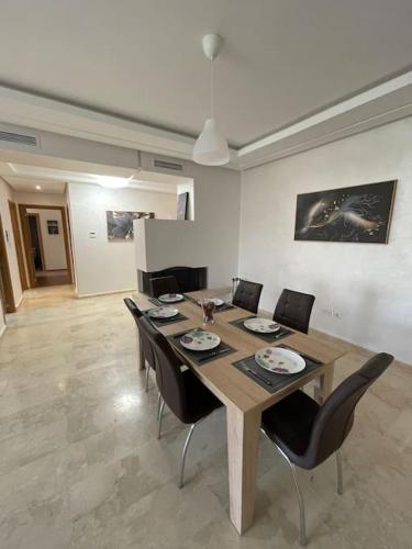 a dining room with a wooden table and chairs at Chic & cosy Flat Near Airport lockbox fast wifi in Nouaceur