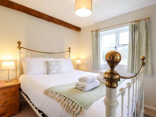 um quarto com uma cama com lençóis brancos e uma janela em The Brambles em Colchester