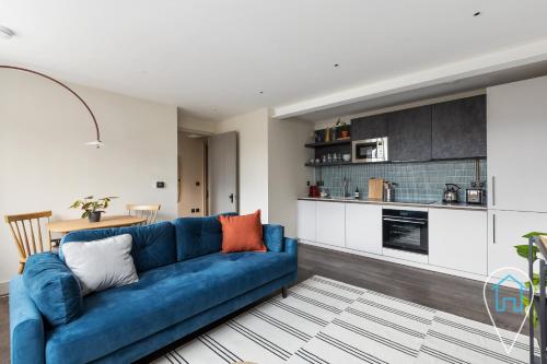 a living room with a blue couch and a kitchen at Modern 1BR home in Islington! in London
