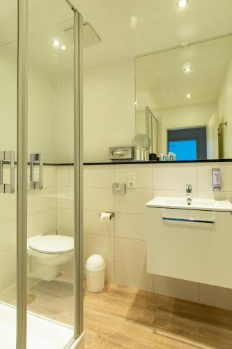 a bathroom with a toilet and a sink and a shower at Hotel am Fischerstrand in Bansin