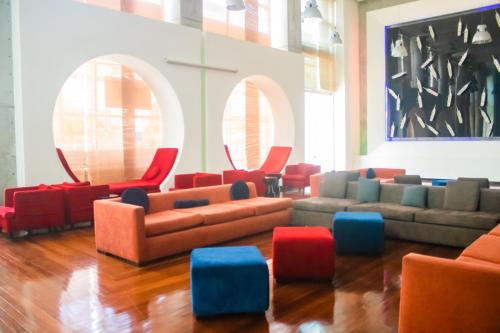 a living room with couches and red and blue chairs at Decapolis Hotel Panama City in Panama City