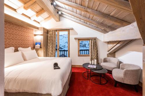 a bedroom with a large white bed and a chair at Hôtel L'Aigle du Montana by Les Etincelles in Tignes