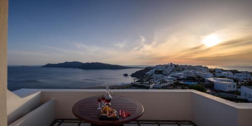 a table on a balcony with a view of the ocean at Nikos Villas in Oia