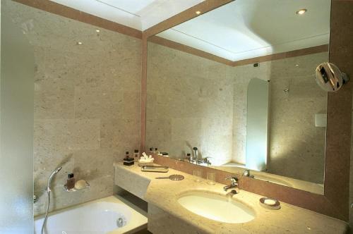 a bathroom with a sink and a tub and a mirror at Hotel La Ville in Catania