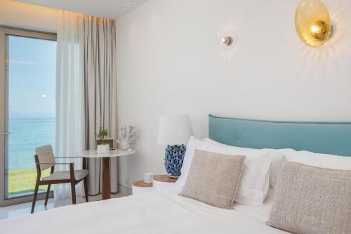a bedroom with a bed and a table with a chair at Domes Miramare, a Luxury Collection Resort, Corfu - Adults Only in Moraitika