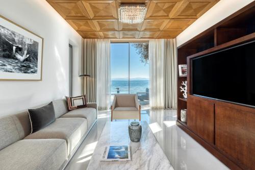 a living room with a couch and a tv at Domes Miramare, a Luxury Collection Resort, Corfu - Adults Only in Moraitika