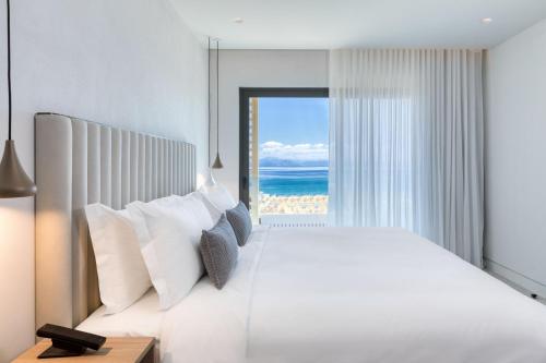 a bedroom with a bed with a view of the ocean at Domes Miramare, a Luxury Collection Resort, Corfu - Adults Only in Moraitika
