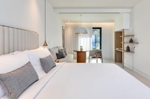 a bedroom with a large white bed and a living room at Domes Miramare, a Luxury Collection Resort, Corfu - Adults Only in Moraitika