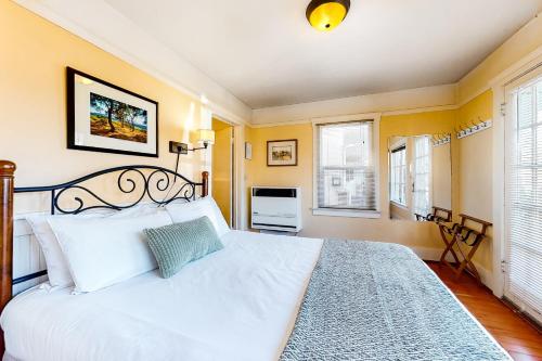 um quarto com uma cama branca e 2 janelas em Beach Hill Bungalow em Santa Cruz