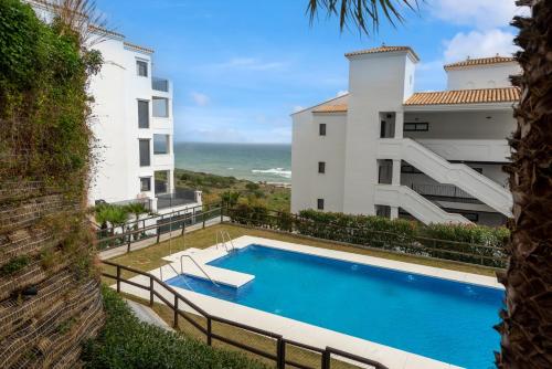 a swimming pool in front of a building with the ocean at Luxurious apartment with sea views Blue Suites B2-103 in Manilva