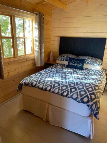 een slaapkamer met een bed in een blokhut bij O Dan Y Coed Swedish Log Cabin with New 2024 Wood Fired Hot Tub in Chwilog