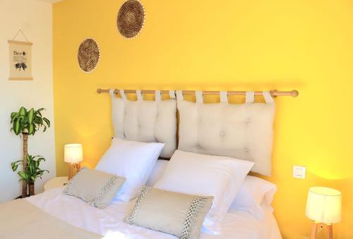 Dormitorio amarillo con cama con almohadas blancas en Bar des Amis en Villars