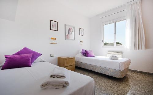 2 bedden in een kamer met paarse kussens en een raam bij R11 Casa Blanca con gran jardin y piscina in Calafell