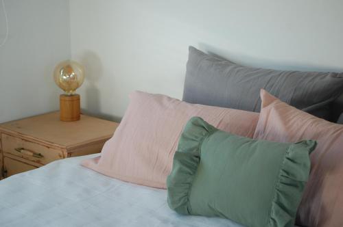 Una cama con almohadas rosas y verdes y una mesa. en Hospedaje Sierra del Tigre II en Tandil