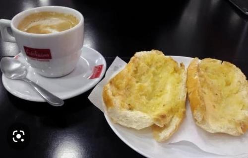 um prato branco com uma chávena de café e uma sanduíche em Meire Hostel em Guarulhos