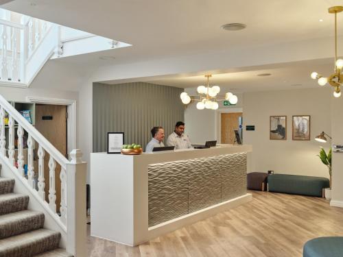two people standing at a counter in a dental office at Linton Lodge a BW Signature Collection Hotel in Oxford