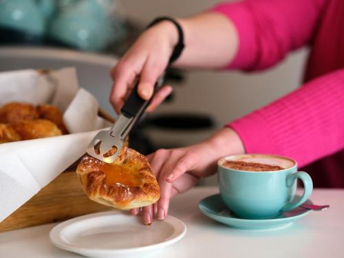 a person cutting a pastry with a fork and a cup of coffee at Linton Lodge a BW Signature Collection Hotel in Oxford