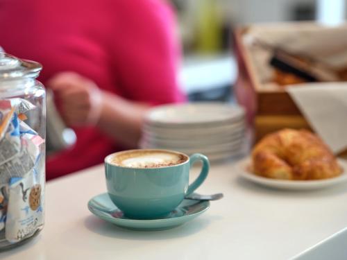 a cup of coffee on a table with a plate of donuts at Linton Lodge a BW Signature Collection Hotel in Oxford