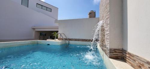 a swimming pool with a water fountain on the side of a building at L & P Apart Punta Hermosa in Punta Hermosa